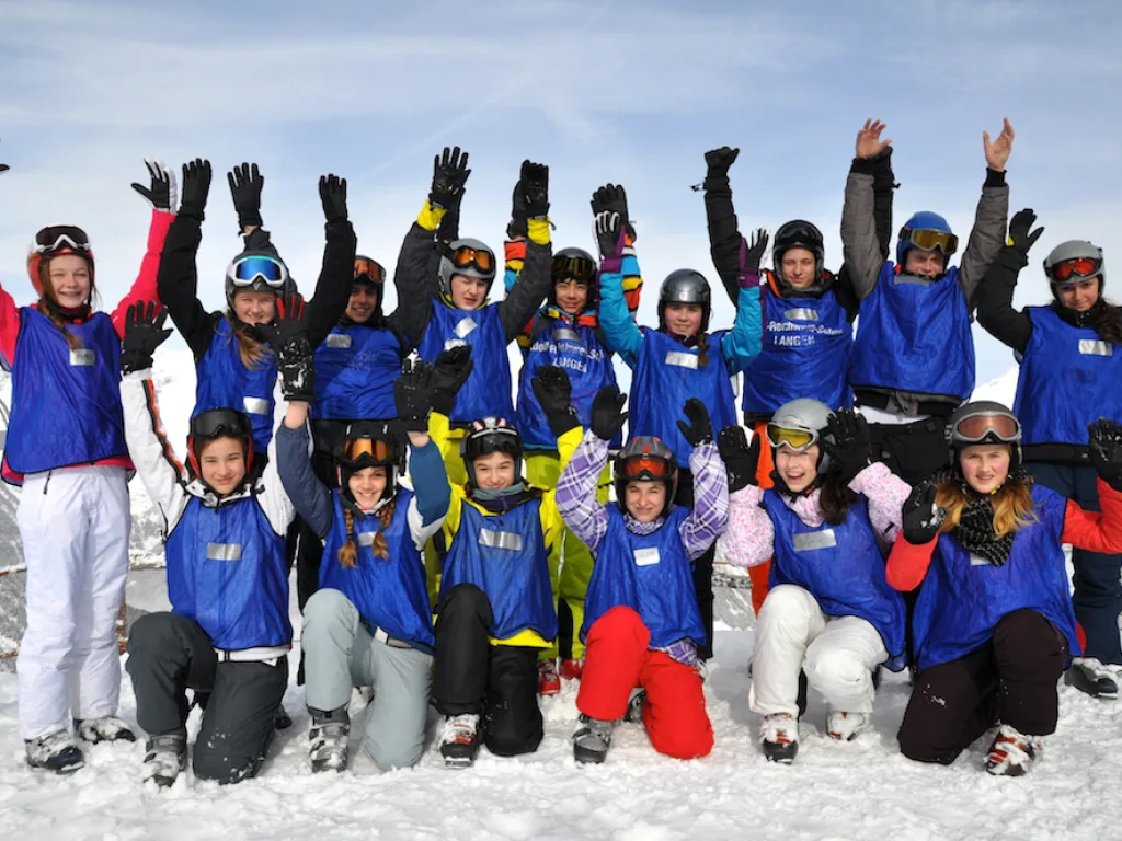 Gruppe posiert jubelnd im Schnee.